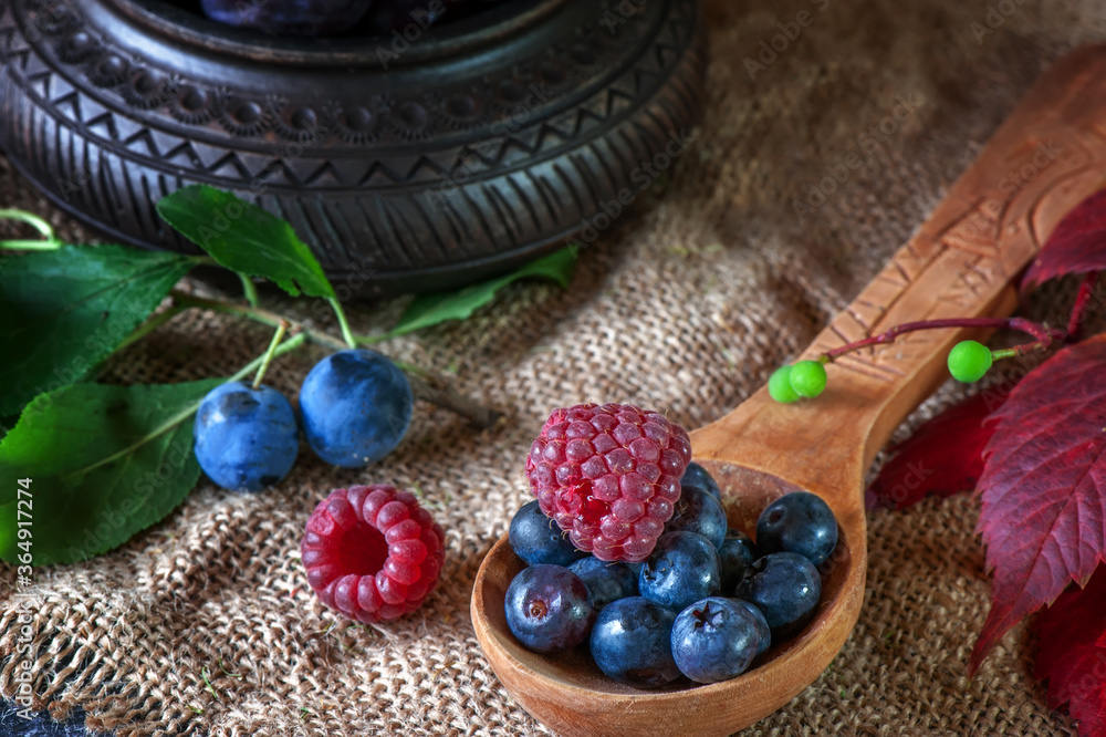 Ripe blueberries, raspberries and blueberries in a wooden spoon for making jam. Close-up, selective focus Ripe blueberries, raspberries and blueberries in a wooden spoon for making jam. Close-up, selective focus