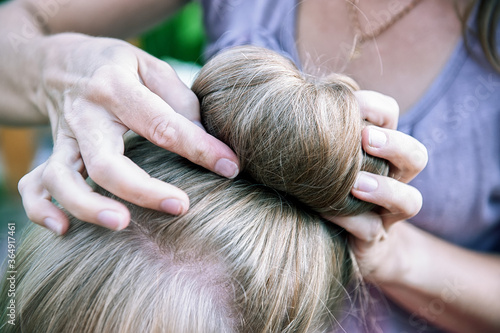 woman's hands plait the girl's hair. A woman does her daughter's hair.