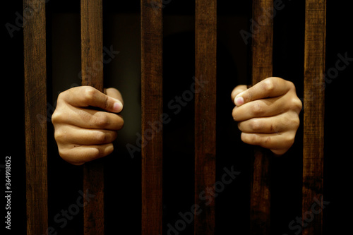 Close-up of the hand of a girl holding a wooden cage in a dark room. Concepts of crime and violence