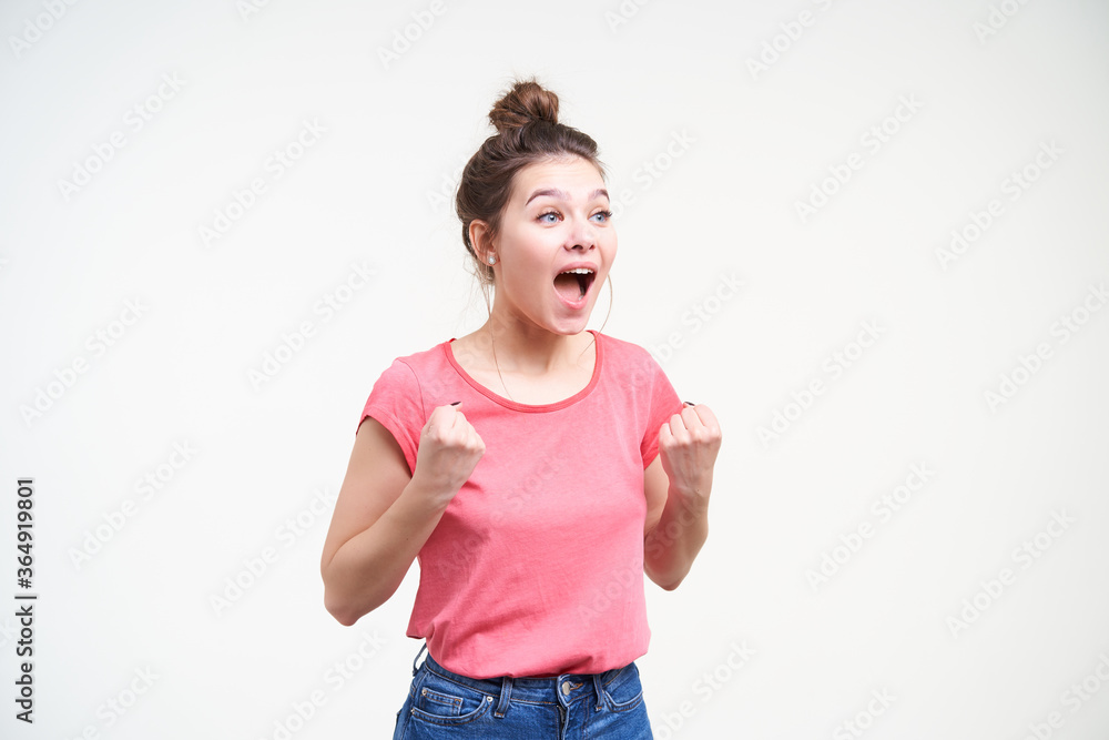 Overjoyed young lovely brunette lady keeping her mouth opened while screaming and raising emotionally her hands while rejoicing about something, isolated over white background Overjoyed young lovely brunette lady keeping her mouth opened while screaming and raising emotionally her hands while rejoicing about something, isolated over white background