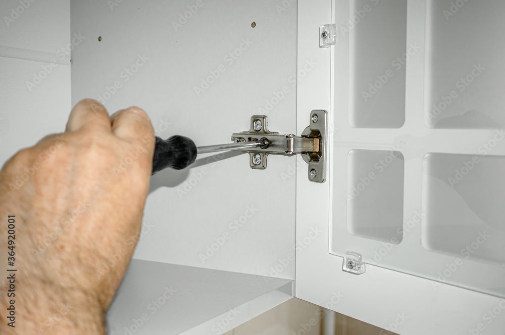 master collects kitchen furniture. Close-up of the master attaching the Cabinet doors. Concept of repair and renovation. copy place master collects kitchen furniture. Close-up of the master attaching the Cabinet doors. Concept of repair and renovation. copy place