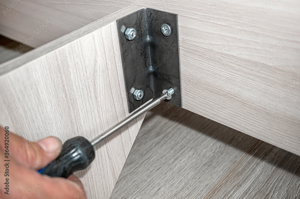 master collects furniture. Close-up of the master connecting the metal corner of the Cabinet details. Concept of repair and renovation. copy space master collects furniture. Close-up of the master connecting the metal corner of the Cabinet details. Concept of repair and renovation. copy space