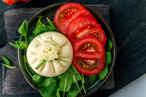 burrata. dinner with tomato and spinach salad with Italian Buratto cheese. Concept of healthy Mediterranean food photo