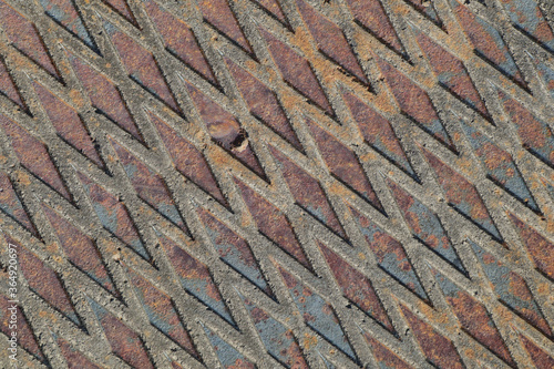 Close-up of a weathered diamond steel plate. Weathering has produced beautiful rust to blue-gray variations. Diamond pattern is angled.