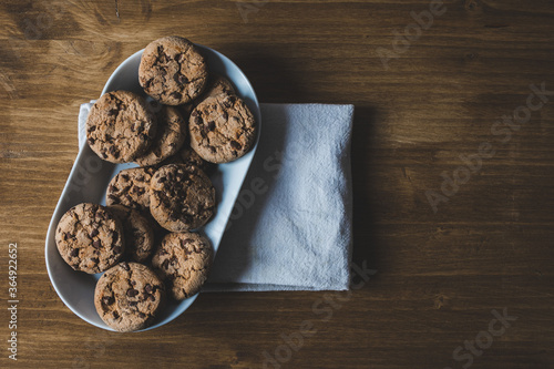 some chocolate cookies with a plate and a napkin on a wooden background