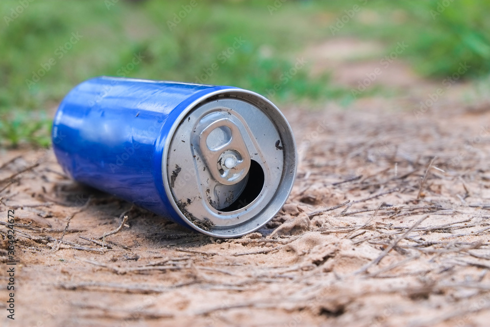 Garbage from blue water aluminum can that are thrown away on the soil ground in garden park which is a problem and pollution to the environment close-up. Garbage from blue water aluminum can that are thrown away on the soil ground in garden park which is a problem and pollution to the environment close-up.