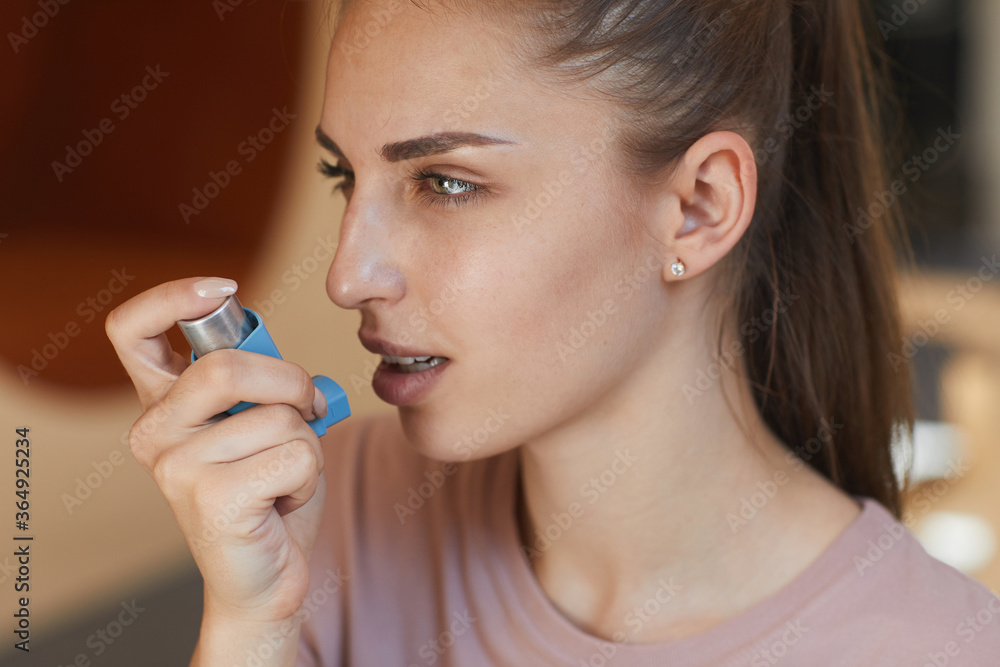 Close-up of attractive girl having breath problem using asthma inhaler to breathe medicine into lungs Close-up of attractive girl having breath problem using asthma inhaler to breathe medicine into lungs