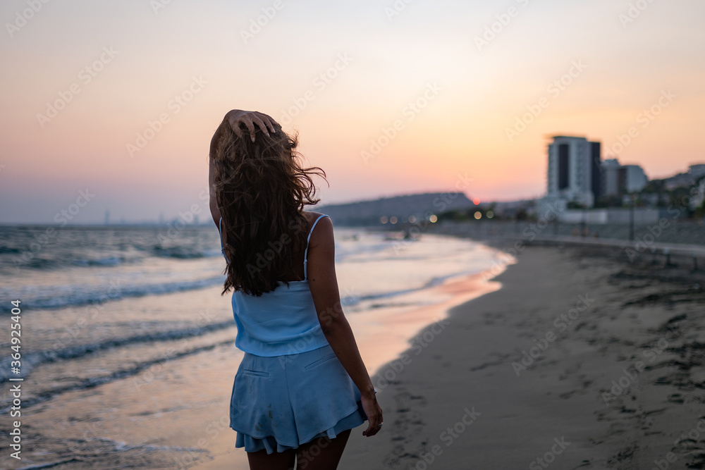 Young woman relaxing walking on beach at sunset in summer