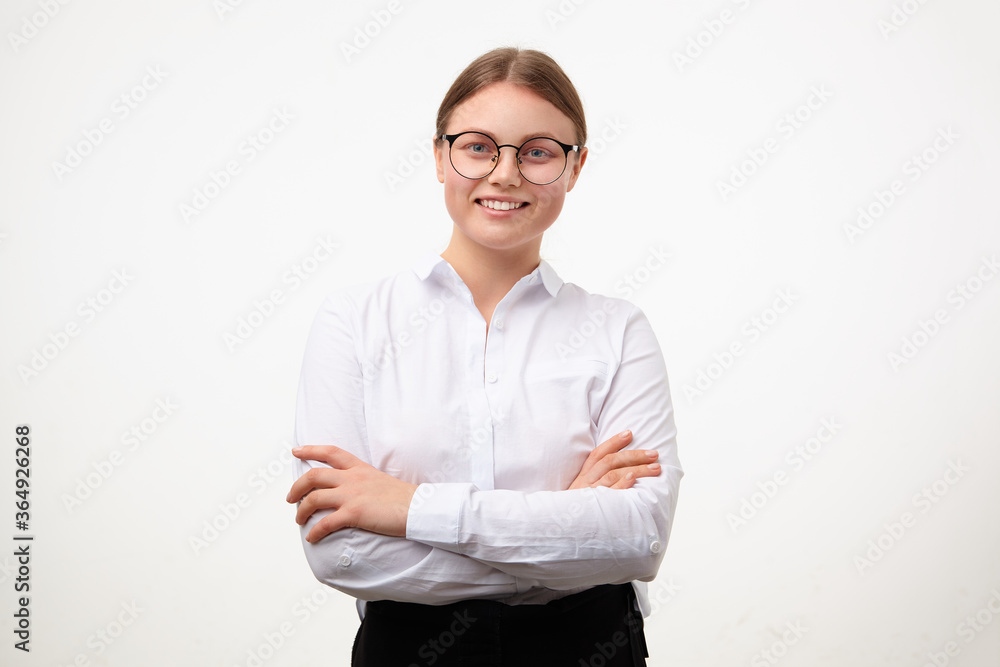 Cheerful young lovely blonde woman in glasses looking gladly at camera with wide smile and keeping hands crossed while standing over white background Cheerful young lovely blonde woman in glasses looking gladly at camera with wide smile and keeping hands crossed while standing over white background