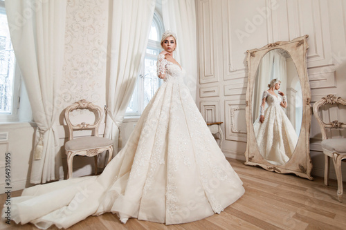 Bride in white dress, blonde girl posing in a photo studio. Vintage style interior.