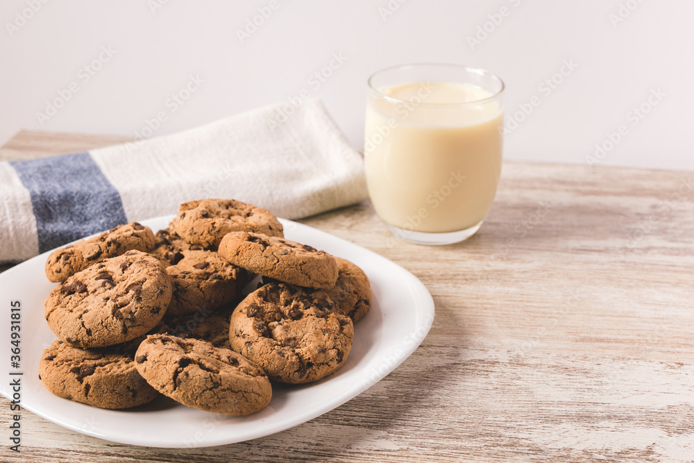some chocolate cookies on a white plate with a glass of milk some chocolate cookies on a white plate with a glass of milk
