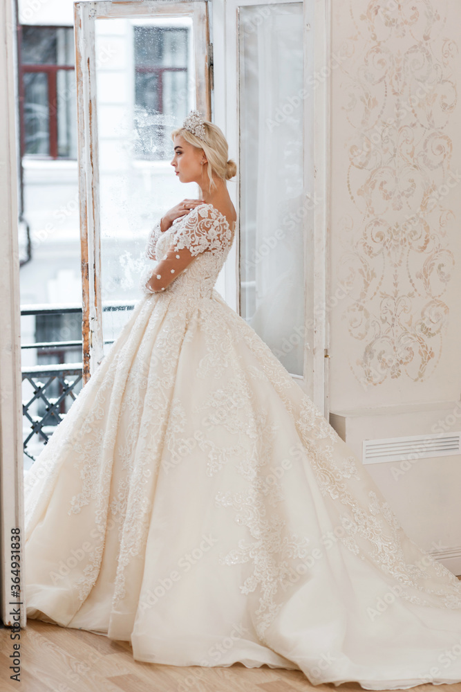 Bride in white dress, blonde girl posing in a photo studio. Vintage style interior.