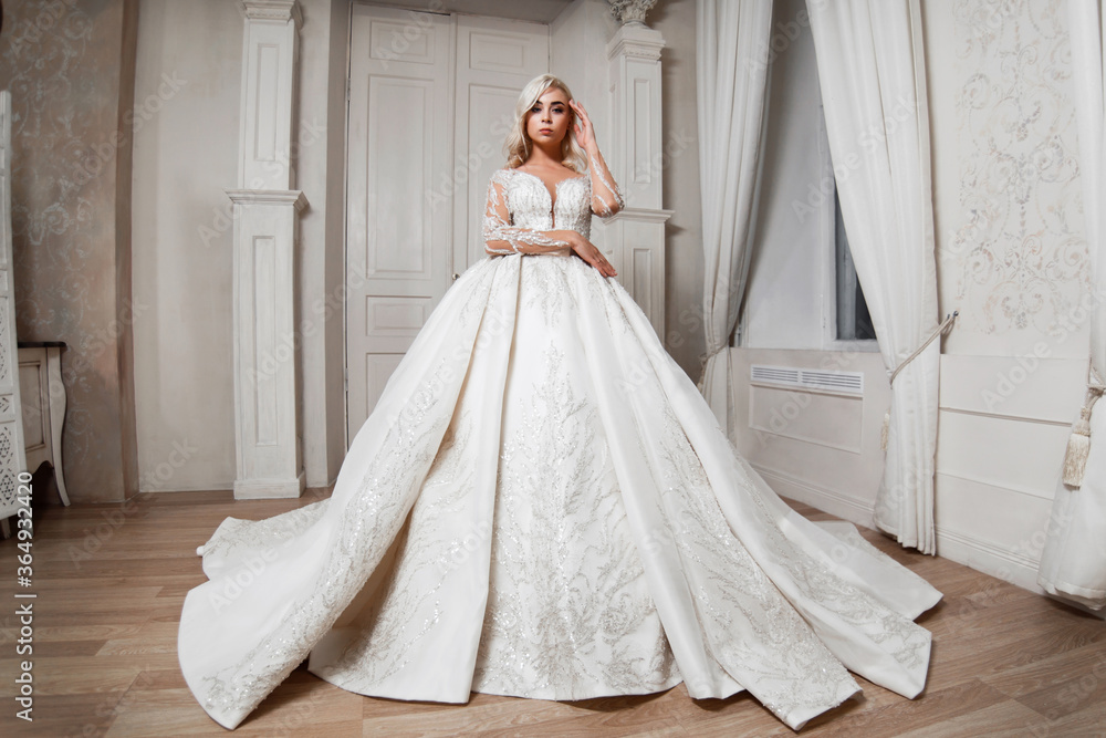 Bride in white dress, blonde girl posing in a photo studio. Vintage style interior. Bride in white dress, blonde girl posing in a photo studio. Vintage style interior.