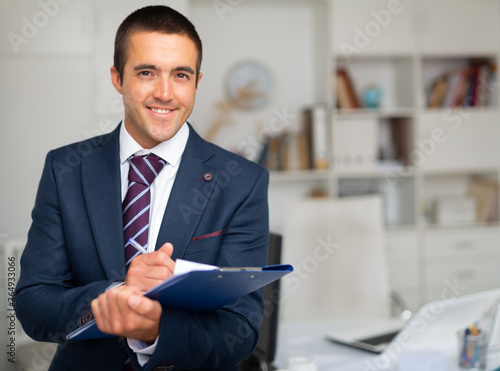 Portrait of positive business man with folder of documents at office