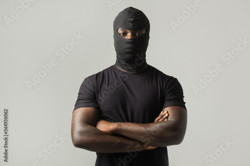 Fotografija young african man in a black mask and a black t-shirt on a gray background