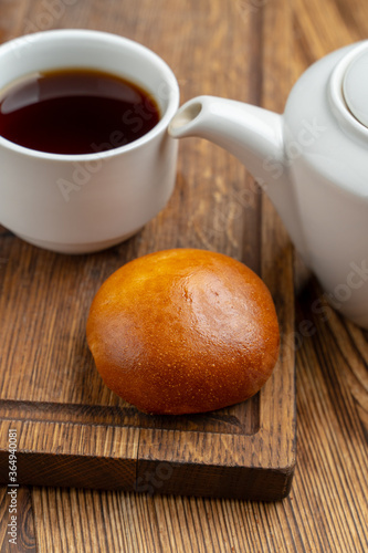 Single russian stuffed pirozhok with black tea on wooden table photo