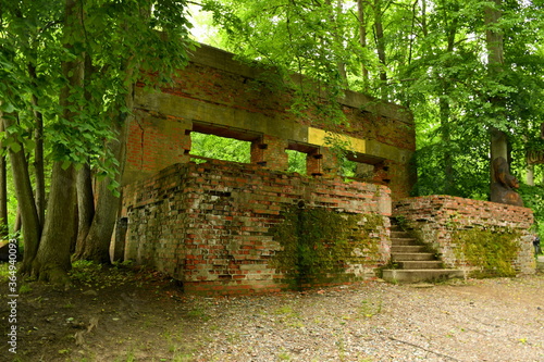 A view of abandoned red brick barracks being the remnant of the Second World War standing in the middle of a forest or moor with some parts of the building missing seen on a sunny day in Poland