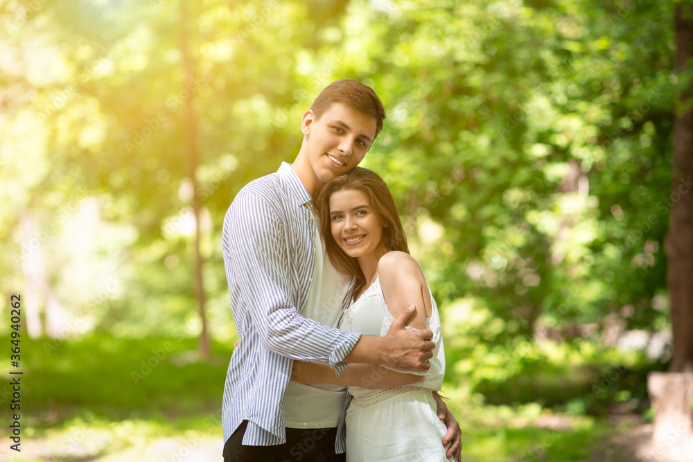 Romantic times together. Millennial couple in love embracing at sunny summer park Romantic times together. Millennial couple in love embracing at sunny summer park