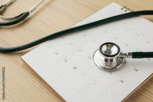 Stethoscope with calendar page date on wood table background doctor appointment medical concept