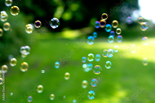 Soap Bubbles in the air, green summer background. Education, family concept. Outdoor fun.