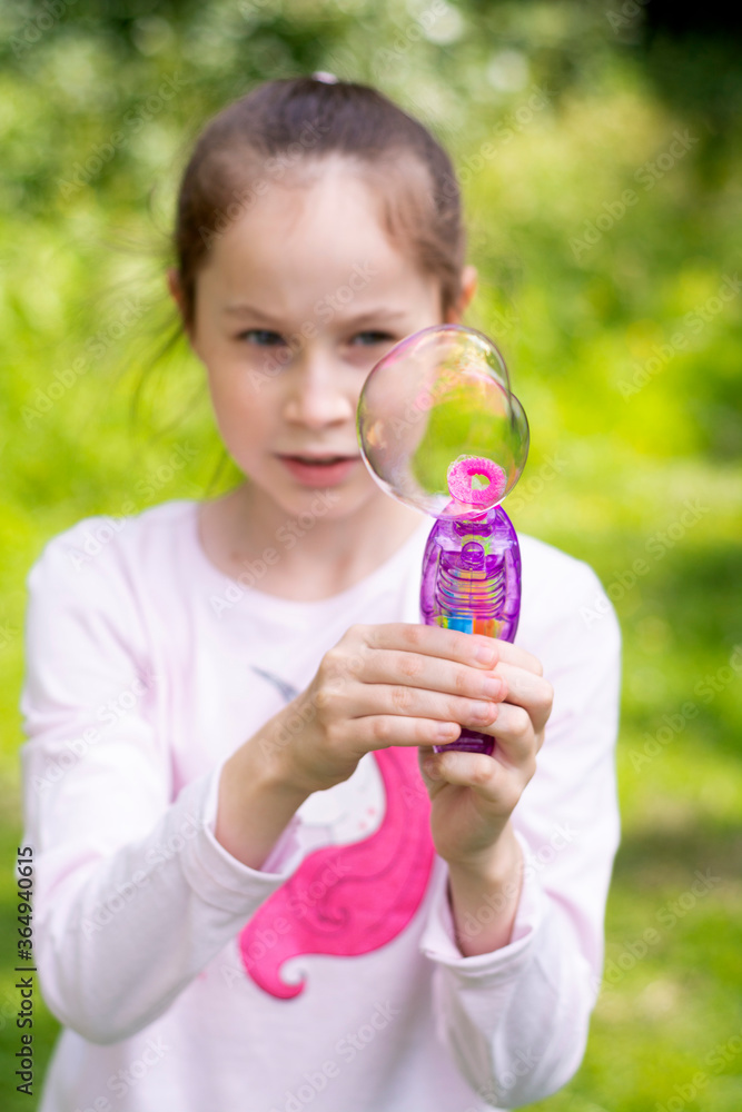 Young, little girl makes soap bubbles outdoor. Summer fun activity for kids. Young, little girl makes soap bubbles outdoor. Summer fun activity for kids.