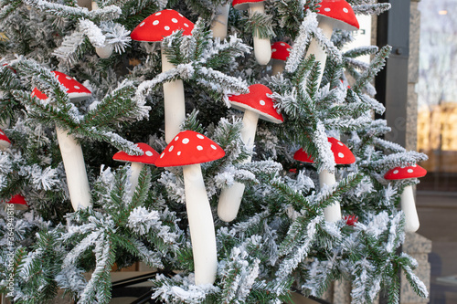 Artificial eco Christmas tree decorated with mushrooms with a red speckled hat with white snow. Decorations on the Christmas tree close-up fly agaric, spruce in the snow photo