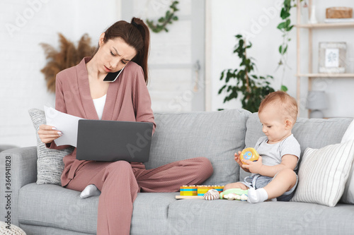 Busy Mother Working Remotely At Home While Taking Care Of Baby