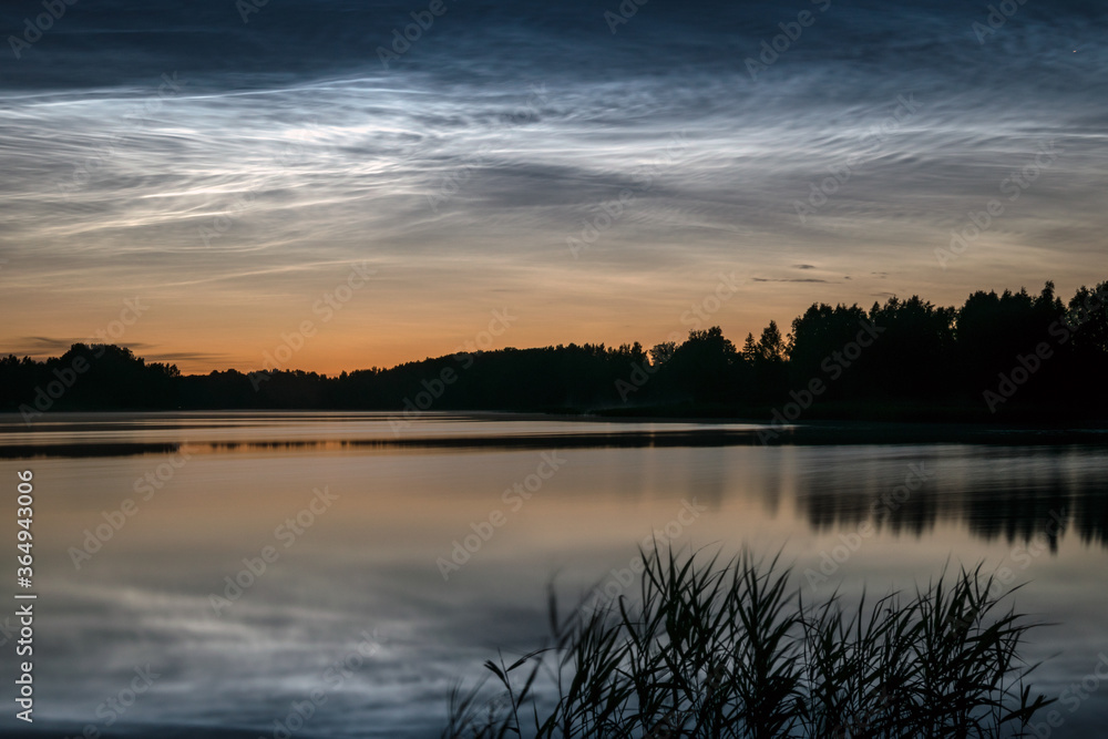 Fototapeta premium night landscape with white silver clouds over the lake, blurred foreground, charming cloud reflections in the lake water, summer night