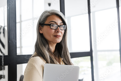Foto Mature business woman standing near window