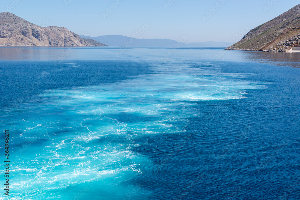 Naklejka premium Water trail foaming behind a ferry boat. Cyclades, Greece.
