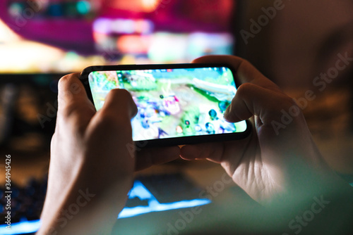 Image closeup of focused man playing video game on mobile phone photo