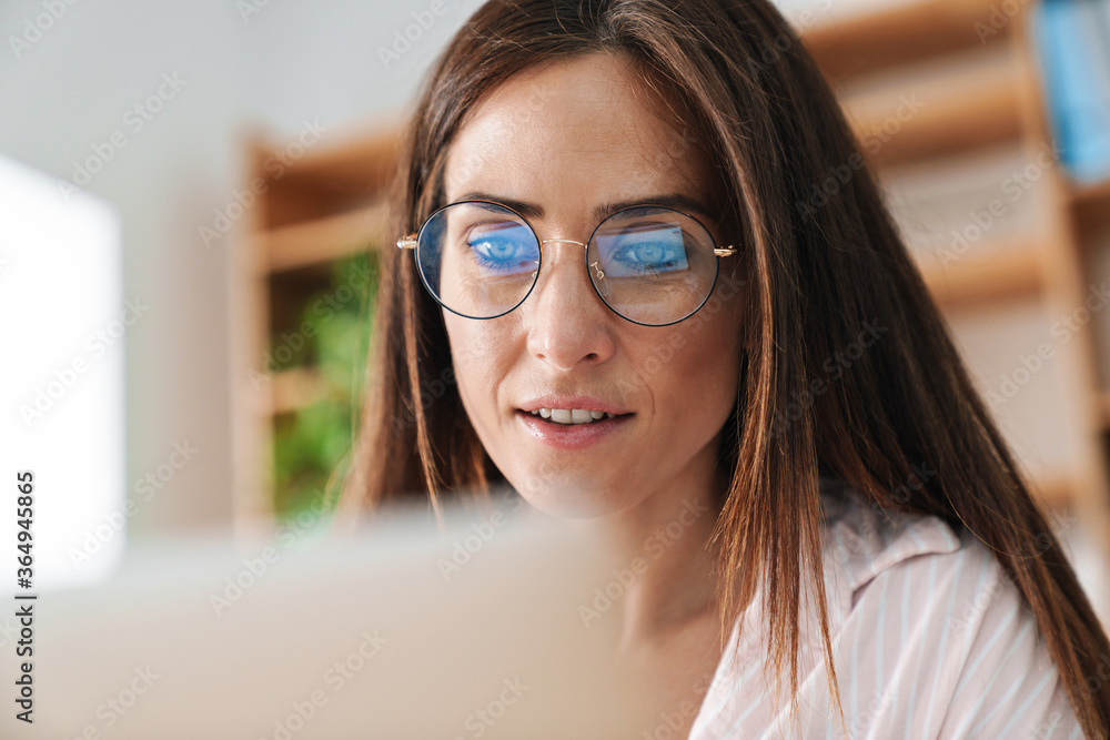 Image of focused adult businesswoman in eyeglasses working with laptop Image of focused adult businesswoman in eyeglasses working with laptop
