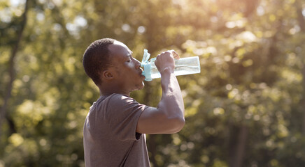 Overheated black guy drinking water from bottle in park