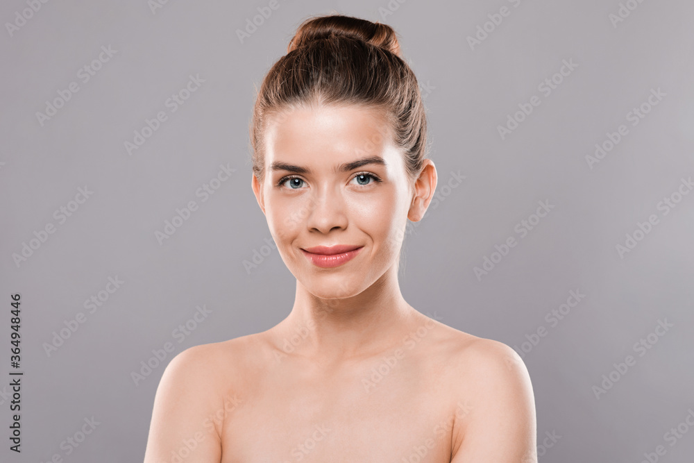 Closeup of naked smiling woman over grey studio background Closeup of naked smiling woman over grey studio background
