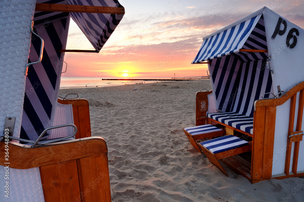 Wschód słońca na wybrzeżu Morza Bałtyckiego,kosze plażowe stoją na piaszczystej plaży w Kołobrzegu,Polska.