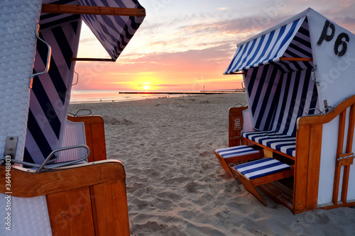 Obraz na płótnie Wschód słońca na wybrzeżu Morza Bałtyckiego,kosze plażowe stoją na piaszczystej plaży w Kołobrzegu,Polska. w salonie
