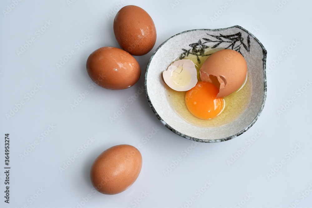 Cracked egg with Yolk egg in ceramic bowl and raw eggs Cracked egg with Yolk egg in ceramic bowl and raw eggs