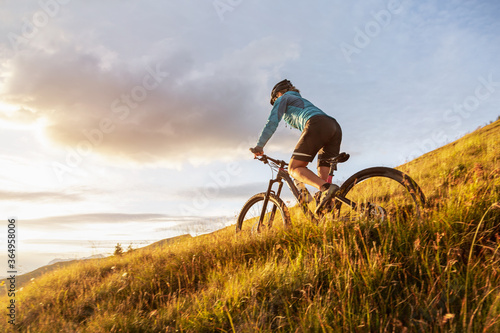 Female mountainbiker riding on a trail in the mountains photo