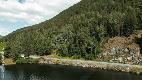 Calm Norwegian country road in the mountains. Nearby calm lake in the summer heat. photo