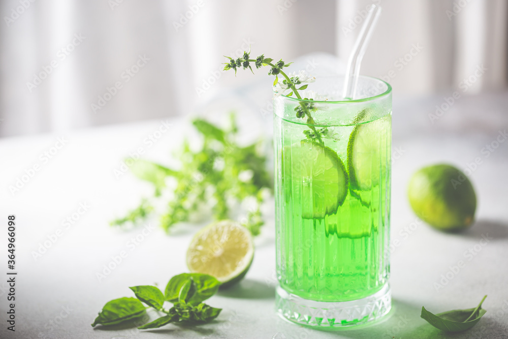 Summer green drink, lemonade with lime, basil and ice in a glass Summer green drink, lemonade with lime, basil and ice in a glass