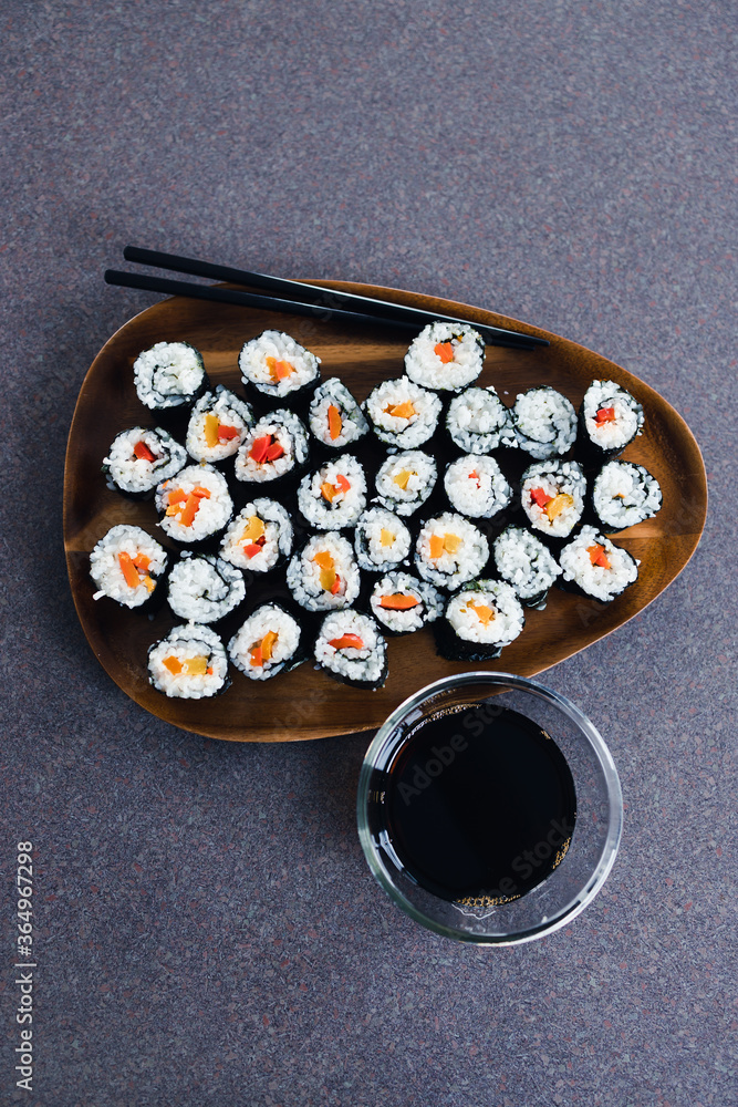 plant-based food, vegan sushi with seaweed and sticky rice with capsicum on serving tray next to bowl with soy sauce plant-based food, vegan sushi with seaweed and sticky rice with capsicum on serving tray next to bowl with soy sauce