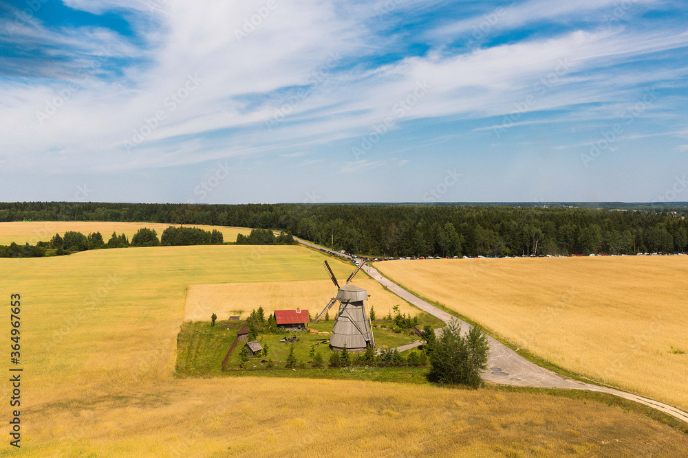 Fototapeta premium Small windmill in the field in belorusian village, view from helicopter. Wheat field in bright sunlight.