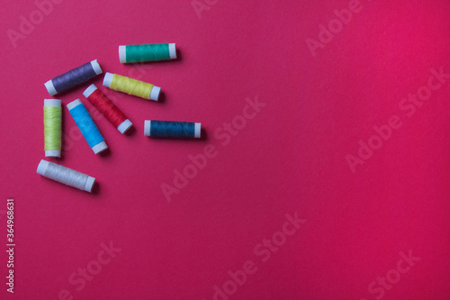 group of spool of threads on red colored paper background, with copy space