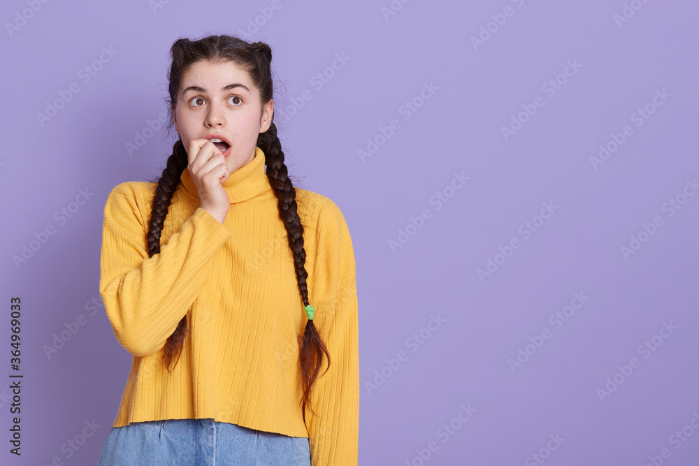Closeup photo of attractive scared lady two pigtails biting fist, looks at camera, feel guilty terrified, wears casual white yellow jumper, isolated over lilac background. Copy space. Closeup photo of attractive scared lady two pigtails biting fist, looks at camera, feel guilty terrified, wears casual white yellow jumper, isolated over lilac background. Copy space.