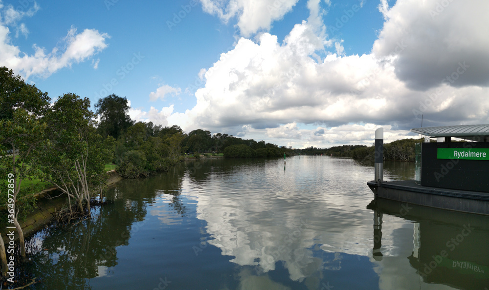 beautiful early morning view of river with reflections of blue sky, clouds and trees on water, Rydalmere Wharf, Parramatta river, Rydalmere, New South Wales, Australia beautiful early morning view of river with reflections of blue sky, clouds and trees on water, Rydalmere Wharf, Parramatta river, Rydalmere, New South Wales, Australia