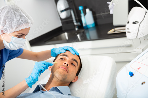 Young man client getting carboxy therapy on face skin, cosmetology beauty treatment at esthetic clinic