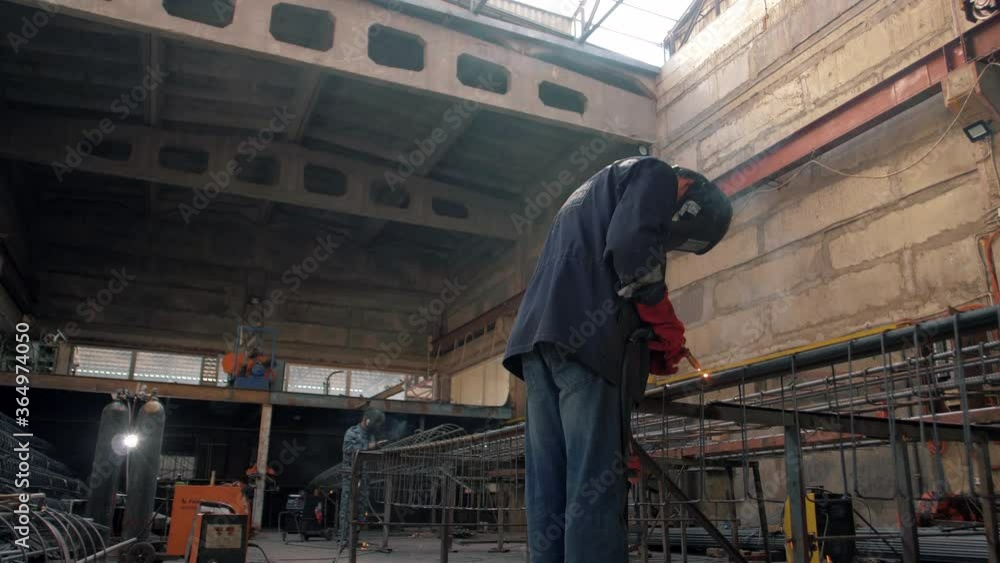 Welders work in a huge sheet-metal shop Welders work in a huge sheet-metal shop