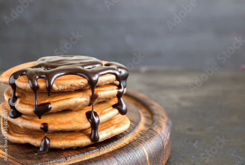 Chocolate pancakes with chocolate syrup on a dark background.