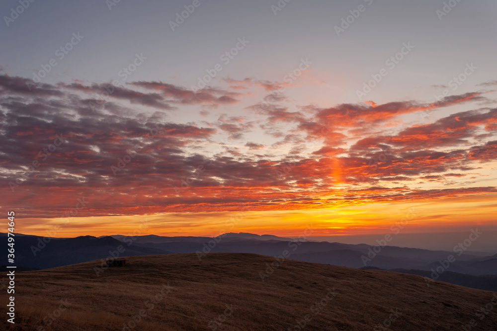 Mountain sunrise under a blanket of red clouds.