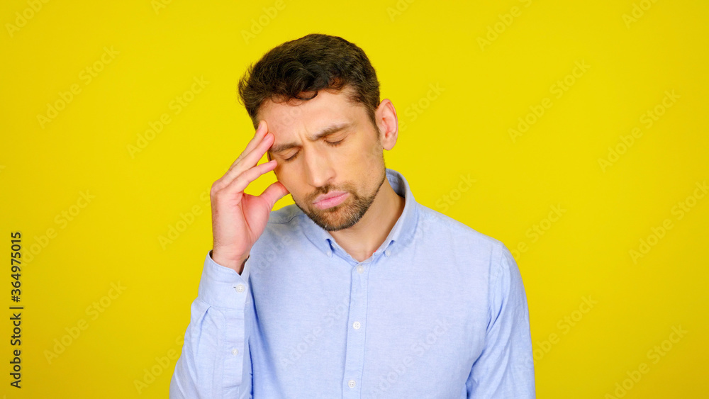 Handsome bearded man with a headache on a yellow background with copy space. Pensive guy rested fingers on head Handsome bearded man with a headache on a yellow background with copy space. Pensive guy rested fingers on head